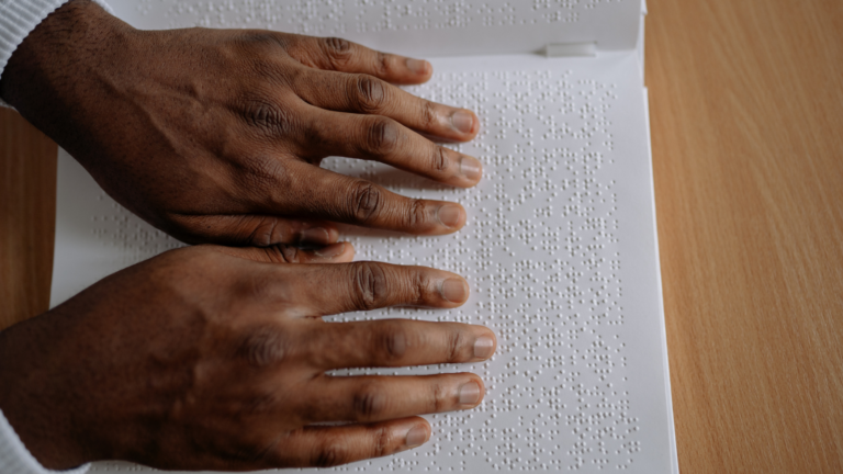 Image of hands on a page reading braille